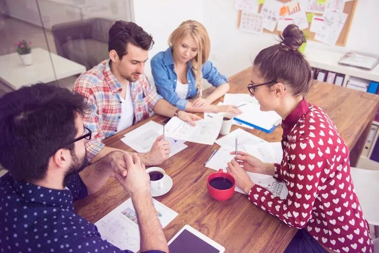 Team diskutiert an einem Tisch voller Unterlagen