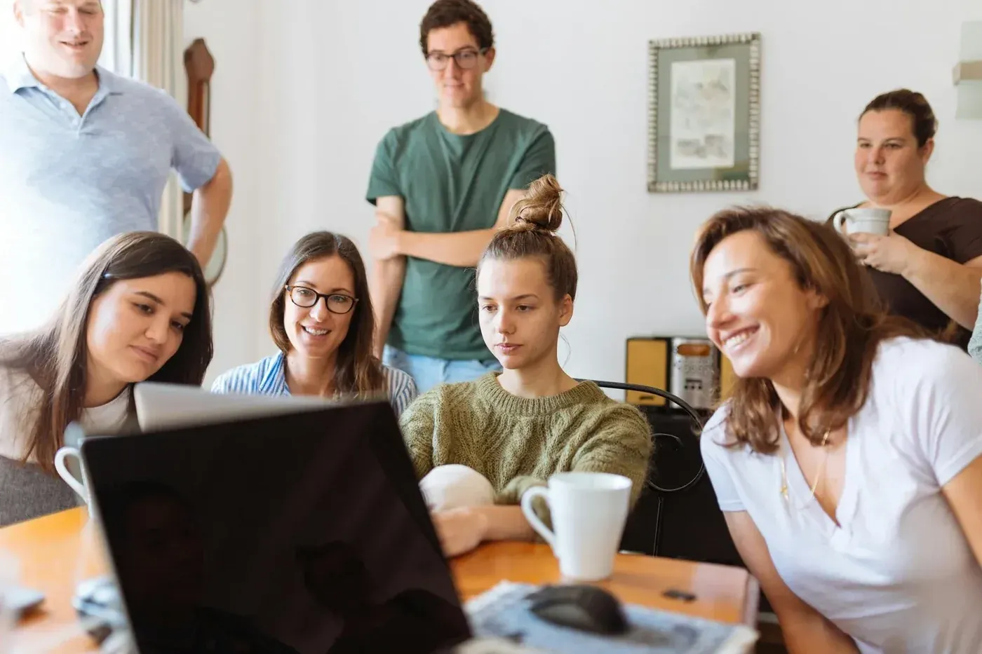 Gruppe arbeitet gemeinsam an einem Tisch mit Laptop und Kaffee